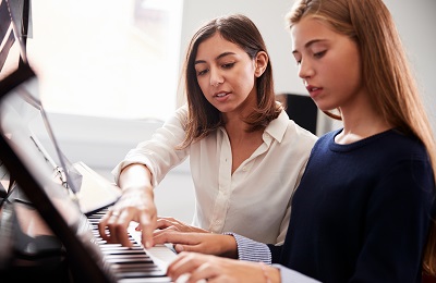 piano teacher and student sitting at piano